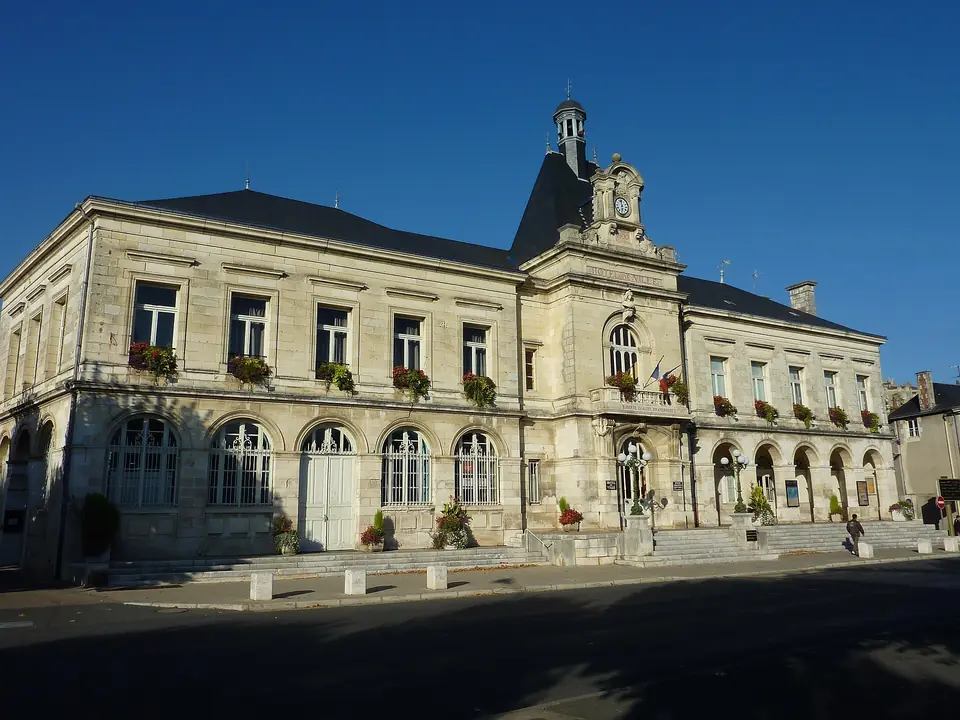 Mairie de Chauvigny, façade en pierre de taille à hautes fenêtres ornées de jardinières, surmontée d'un campanile.