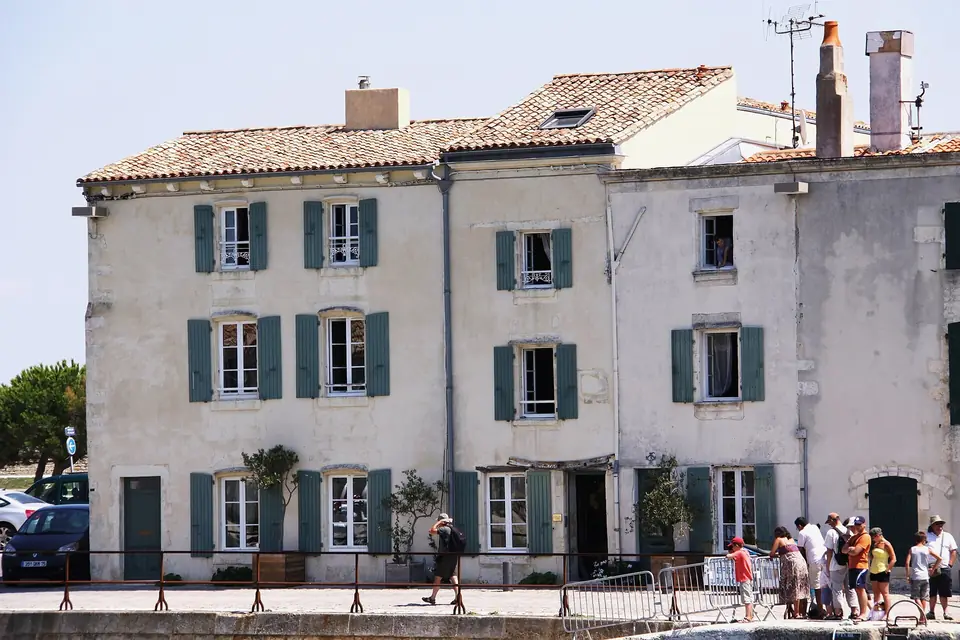 Maisons en pierre du quai Clemenceau à Saint-Martin-de-Ré, façades claires percées de nombreuses fenêtres à volets verts.